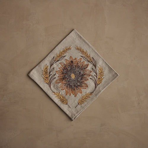 Coral & Tusk Sunflower and Wheat embroidered linen 20 × 20-inch folded dinner napkin featuring a sunflower centered within a wreath of golden wheat, designed in warm seasonal hues.