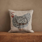 Coral & Tusk 16 × 16-inch embroidered linen Mother Hen Pocket Pillow featuring a black-and-white feathered Mother Hen with a liftable wing revealing two removable chicks tucked in a pocket.