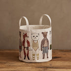 Coral & Tusk Pocket Dolls Bucket, a cylindrical canvas storage basket with two top handles, angled to showcase Fox, Baby Cat and Bear within an all-over embroidered pattern of standing Coral & Tusk pocket doll characters on an off-white background.