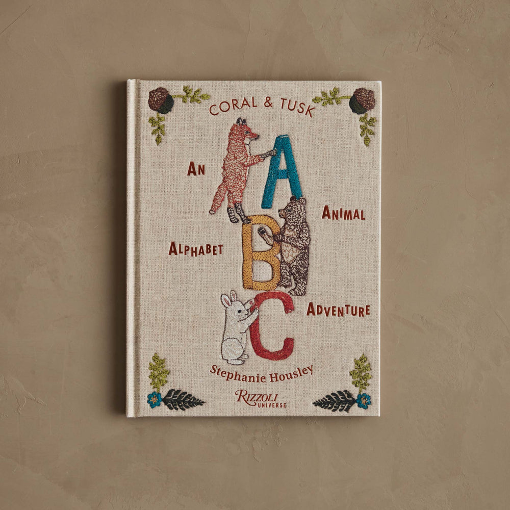 Book titled 'Coral & Tusk: An Alphabet Animal Adventure' by Stephanie Housley on a brown background.
