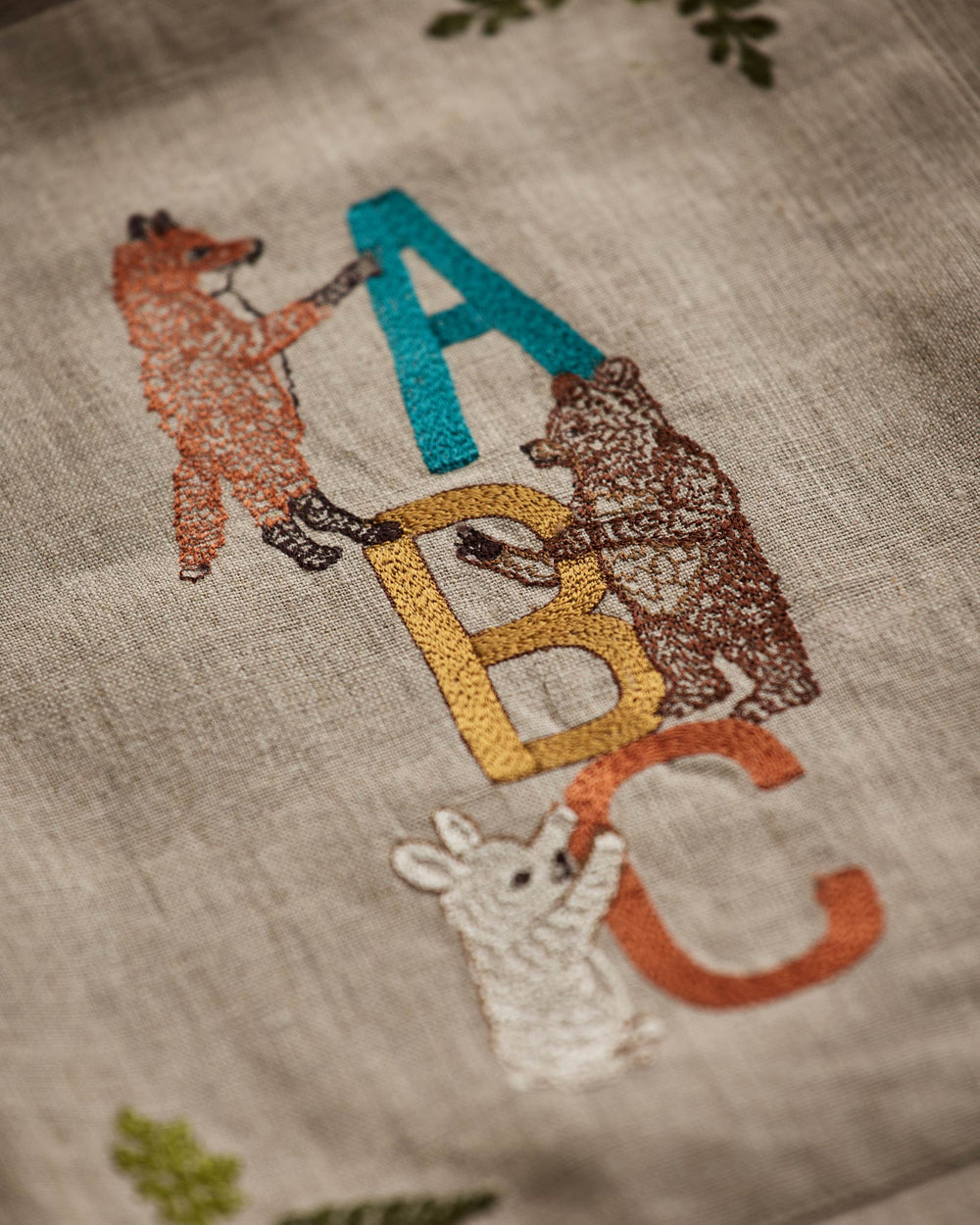 Close-up of Coral & Tusk ABC Tote Bag showing embroidered detail with fox, bear, bunny and letters 'A', 'B', 'C' on natural linen.