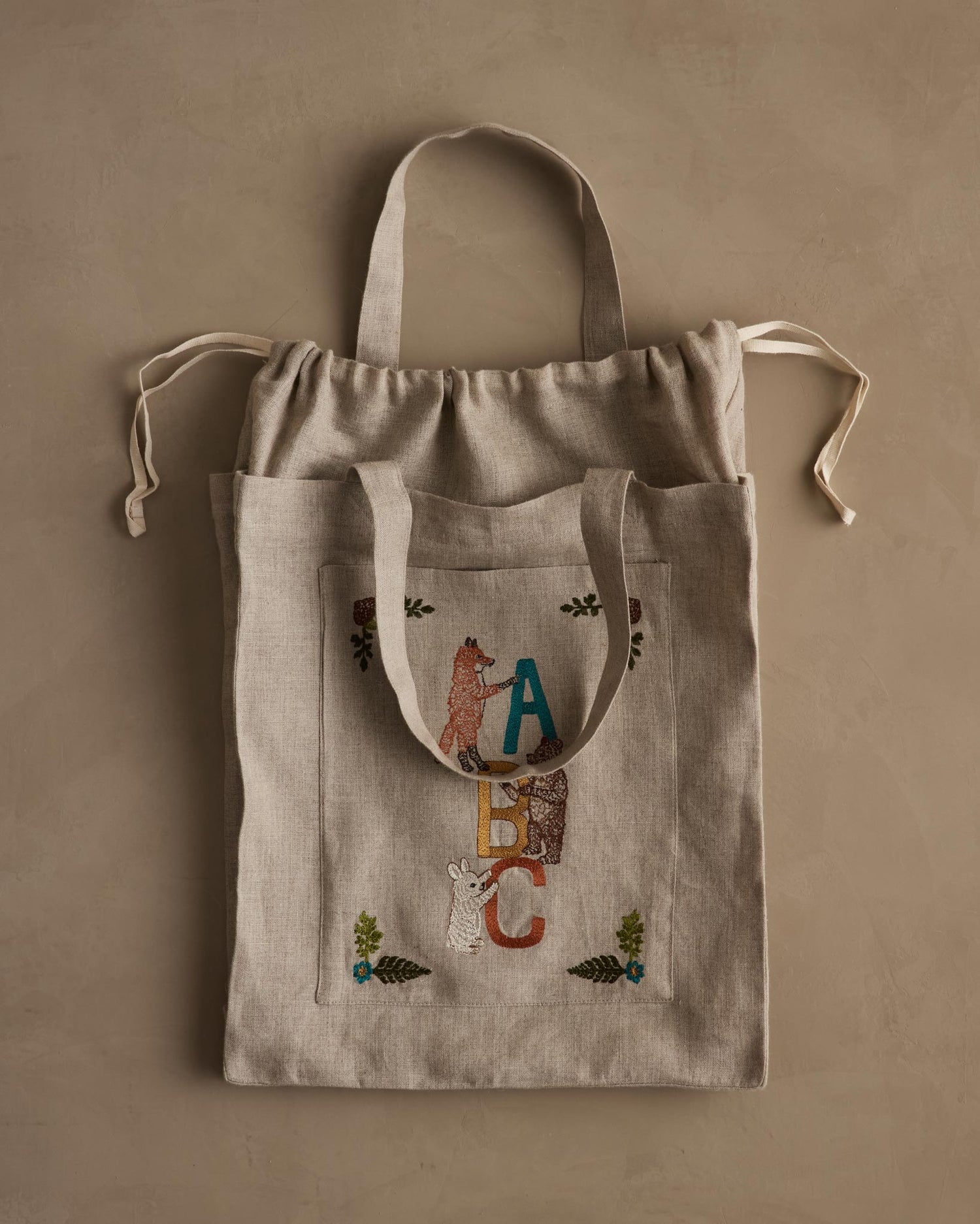 Coral & Tusk linen ABC Tote Bag with drawstring closure and front pocket with embroidered ABC letters, fox, bear and bunny animals.